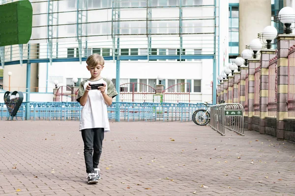 Een Kleine Jongen Onderweg Speelt Zijn Telefoon Terwijl Hij Door — Stockfoto