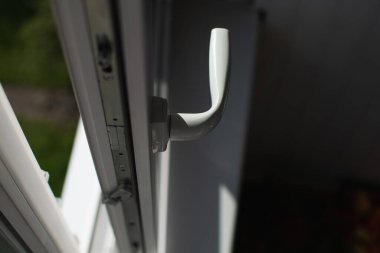 Kemerli plastik balkon penceresi. Çerçeve beyaz, kuşak hafif açık. Cama vuran güneş ışınları