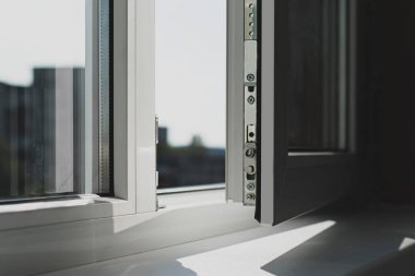 Kuşak plastik balkon penceresi. Çerçeve beyaz, kuşak hafif açık. Cama vuran güneş ışınları