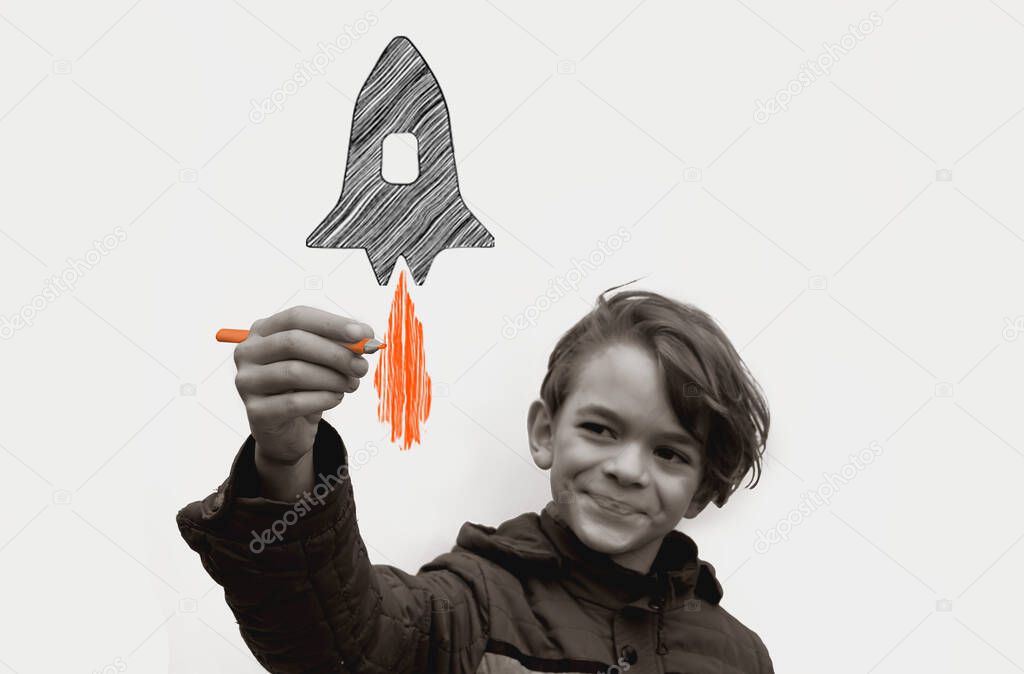 A little boy draws a pencil space rocket soaring into the sky