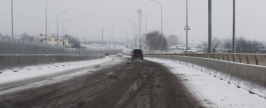 Kışın yol kenarında bulanık bir görüntü. Karla kaplı kaygan yol