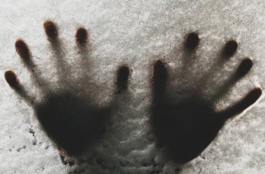 Soğuk kış havasında kar kaplı bir arabanın camında el izleri.