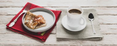 Dekoratif beyaz bir masada bir fincan kahve ve bir tabak krep.