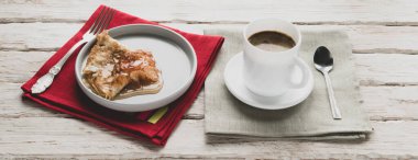 Dekoratif beyaz bir masada bir fincan kahve ve bir tabak krep.