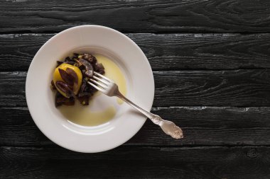 Patatesli beyaz tabak, kızarmış soğan ve dekoratif siyah arka planda çatal.