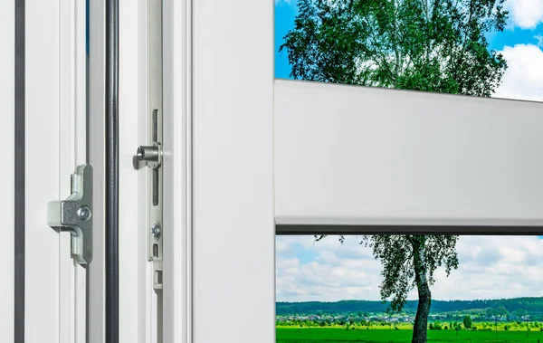 Fragment of an open white plastic window with metal fittings