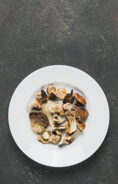 Dekoratif bir arka planda beyaz tabakta kurutulmuş yenebilir mantarlar.