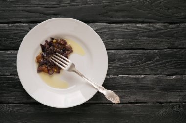 Patatesli beyaz tabak, kızarmış soğan ve dekoratif siyah arka planda çatal.