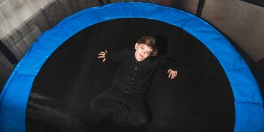 Küçük bir çocuk dairesindeki güvenlik ağıyla trambolinde zıpladıktan sonra dinleniyor.