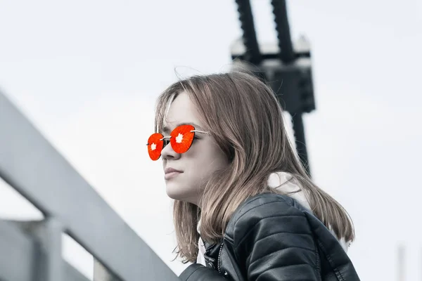 Młoda Dziewczyna Okularach Skórzanej Kurtce Spaceruje Parku Pobliżu Mostu Wiszącego — Zdjęcie stockowe