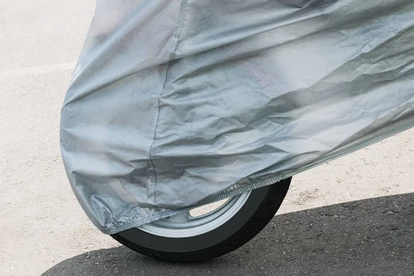 A fragment of a motorcycle in the parking lot, covered with a protective film