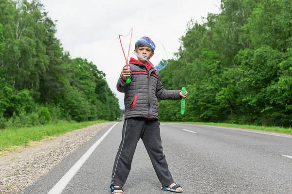 Mały Chłopiec Bawi Się Autostradzie Poza Miastem Dmuchając Bańki Mydlane — Zdjęcie stockowe