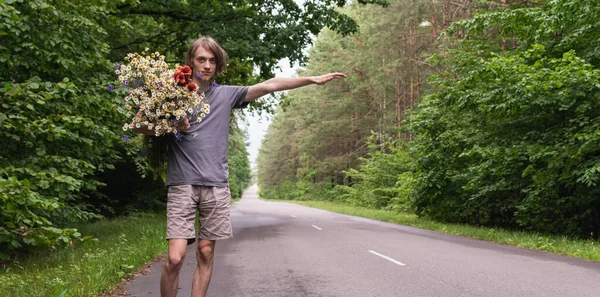 Młody Facet Kwiatami Leśnej Drodze Zatrzymuje Samochód — Zdjęcie stockowe