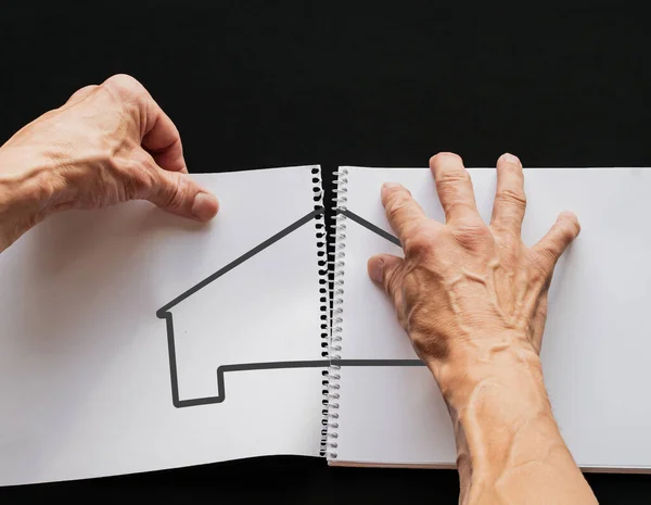 Yetişkin bir adam, dikişli bir albümden bir çizimle çarşafı koparır.