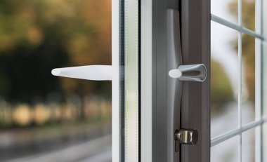 Beyaz bölümleri olan yeni plastik bir pencere ve bir kır evinde kilitli bir kapı kolu.