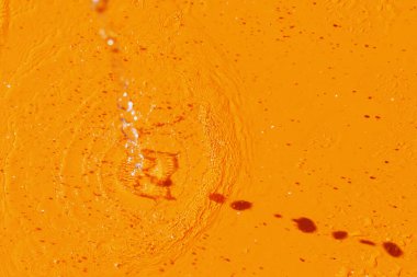 Turuncu bir arka planda, dökülen suyun görüntüsü