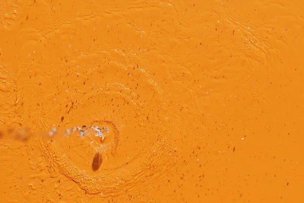 Kilátás Öntő Víz Fröccsenő Narancssárga Alapon — Stock Fotó