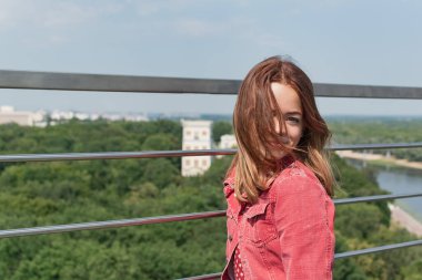 Genç bir kız gözlem güvertesinde panoramik bir balkondan şehre bakıyor.