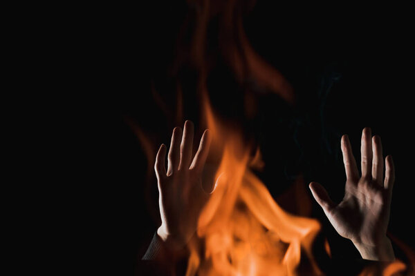 A view of human hands through the fire in complete darkness