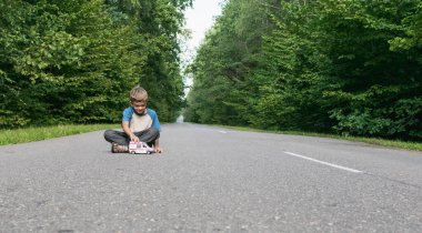 Küçük bir çocuk yolda oyuncak bir ambulansla oynuyor.