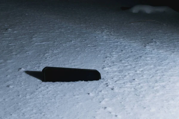 Ένα Χαμένο Μαύρο Τηλέφωνο Βρίσκεται Στο Χιόνι Μια Χειμωνιάτικη Νύχτα — Φωτογραφία Αρχείου