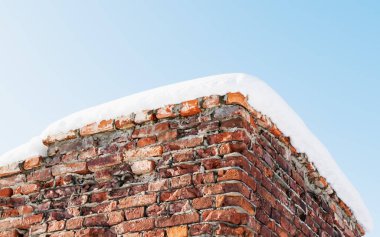 Güneşli bir günde, kar altında harabe bir tuğla kalenin kalıntıları.