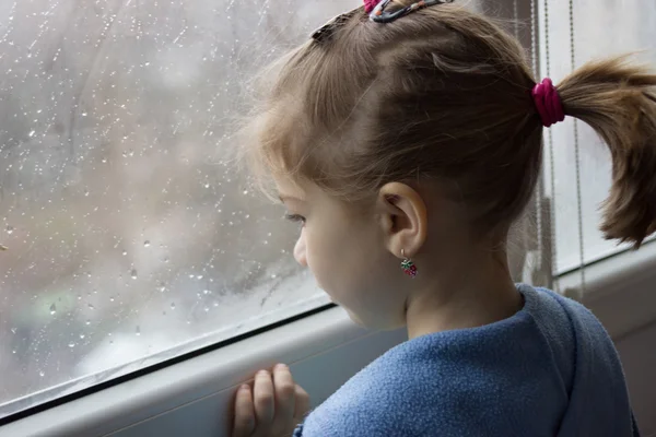 Mädchen blickt bei Regen aus dem Fenster — Stockfoto