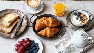 Beyaz ahşap masa, kruvasan reçel kahve portakal suyu. Geleneksel kahvaltı.