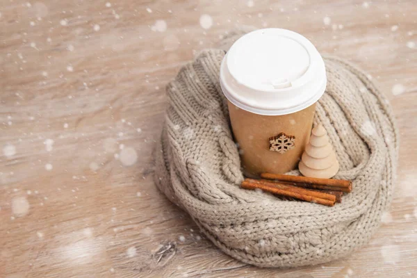 Xícara de papel de café embrulhado em um chapéu de Papai Noel em um fundo de Natal branco e de madeira. — Fotografia de Stock