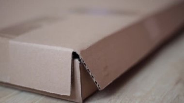 Adam kaseti keser ve karton kutuyu açar.