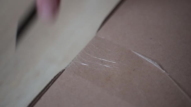 Man cuts the tape on the box and opens the cardboard box — Stock Video