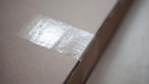 Man cuts the tape on the box and opens the cardboard box — Stock Video