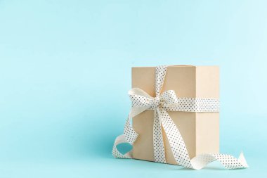 Kraft hediye kutusu, kurdele yayı ve pastel mavisi arka planda kar taneleri ve metin için yer var. noel kartını kopyala 