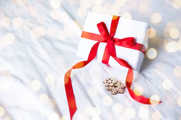 Valkoinen kraft lahjapaketti punainen nauha keula ja lumihiutaleet valkoisella taustalla paikka tekstiä. kopioi tilaa joulukortti — kuvapankkivalokuva