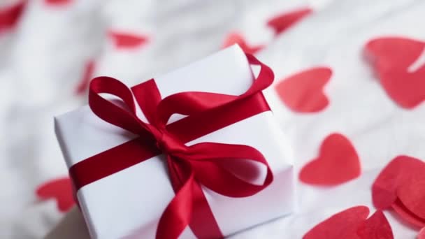 情人节礼物盒放在宾馆的床上 盒子上有红丝带和纸心 — 图库视频影像