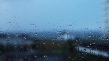 Pencereye düşen yağmur damlaları mavi camlar. Cam yüzeyine damlatıyor. Su damlaları düşüyor. Yağmurlu hava.