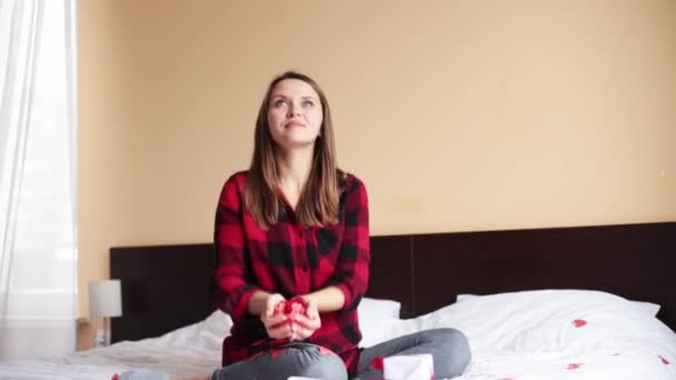 Souriante jeune femme soufflant confettis en forme de coeur des mains, célébration de la Saint-Valentin — Video