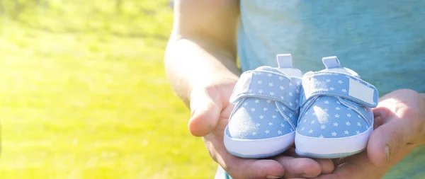 Papá espera el nacimiento de su primer hijo. Hombre sosteniendo pequeños zapatos azules en las manos. Concepto de padres felices. Concepto de embarazada. — Foto de Stock