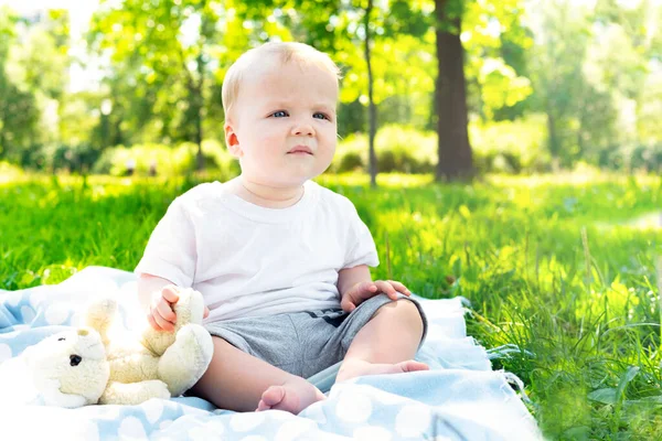공원의 풀밭에서 놀고 있는 귀여운 코카서스 금발의 작은 남자 아이의 모습. 행복 한 어린 시절의 개념 — 스톡 사진