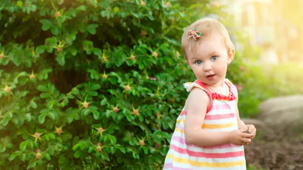 Portrait of little cute caucasian blond baby girl playing outdoors in the grass in the park. happy childhood concept — Stock Photo, Image