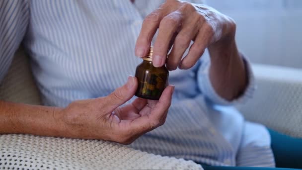 薬瓶から2本のカプセルを注ぐ鎮痛薬を手に持つシニア成人女性の手のビューを閉じます。おばあちゃん薬飲んでる。健康管理だ。薬局と治療のコンセプト — ストック動画
