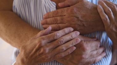  close up of wrinkled hands Cheerful Elderly couple in love embracing at home. old adult pensioners family hugging. seniors comfort each other