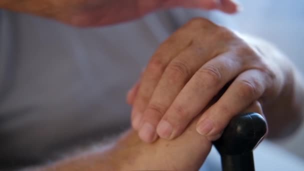 手握着手杖的老年残疾老人。老女人皱着眉头摸着一个退休老人的手。男性健康问题伤害。概念支持和孤独 — 图库视频影像