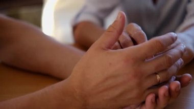 Endişeli beyaz bir adam, yaşlı hasta annesinin şefkatini ya da sevgisini nazikçe okşuyor. Oğul, yaşlı annenin kırışık koluyla yatakta oturuyor. Adam eski ebeveynine destek oluyor..