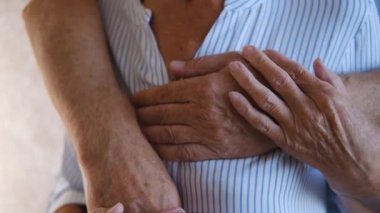  close up of wrinkled hands Cheerful Elderly couple in love embracing at home. old adult pensioners family hugging. seniors comfort each other