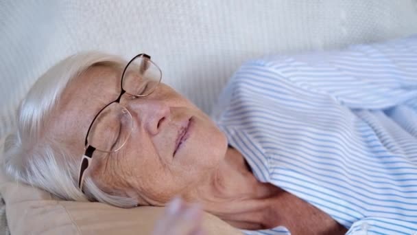 Tutup potret wanita tua bahagia Kaukasia yang sedang tidur atau bersantai di sofa nyaman di rumah. Tidur siang atau bermeditasi wanita tua beristirahat di sofa. bebas stres, konsep perdamaian — Stok Video