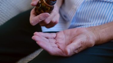  Yetişkin bir kadının elinde ağrı kesici haplarla ilaç şişesinden iki kapsül dökerken görüntüsünü kapatın. Yaşlı büyükannem ilaç alıyor. Sağlık hizmeti. eczane ve tedavi kavramı