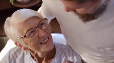 Yakından çekilmiş bir portre yaşlı olgun 60 'lı yaşlarda bir anne büyümüş yakışıklı bir çocukla konuşuyor. Sevgi ve özeni ifade etmek anneler günü konseptine sarılmak. 2 kuşak aile 