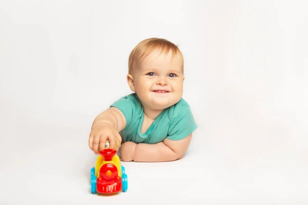 Mooie schattige baby jongen rollen een speelgoedauto op de vloer. een kind dat met een speelgoedtrein speelt. kindertijd, kinderen en mensen concept Stockafbeelding