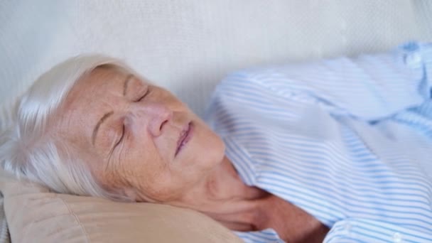 Close up portrait of caucasian happy calm elderly woman sleeping or relax on comfortable sofa at home. taking nap or meditate old lady rest on couch. stress free, peace concept — Stock Video